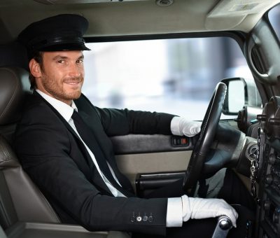 Handsome smiling chauffeur driving limousine.